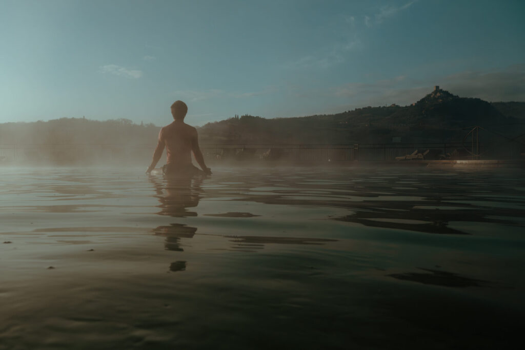 Uomo che pratica yoga sul bordo della vasca termale